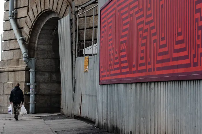 someone walks past a red poster in Dumbo